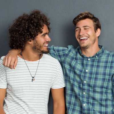 Two young men smile and joke together as friends.